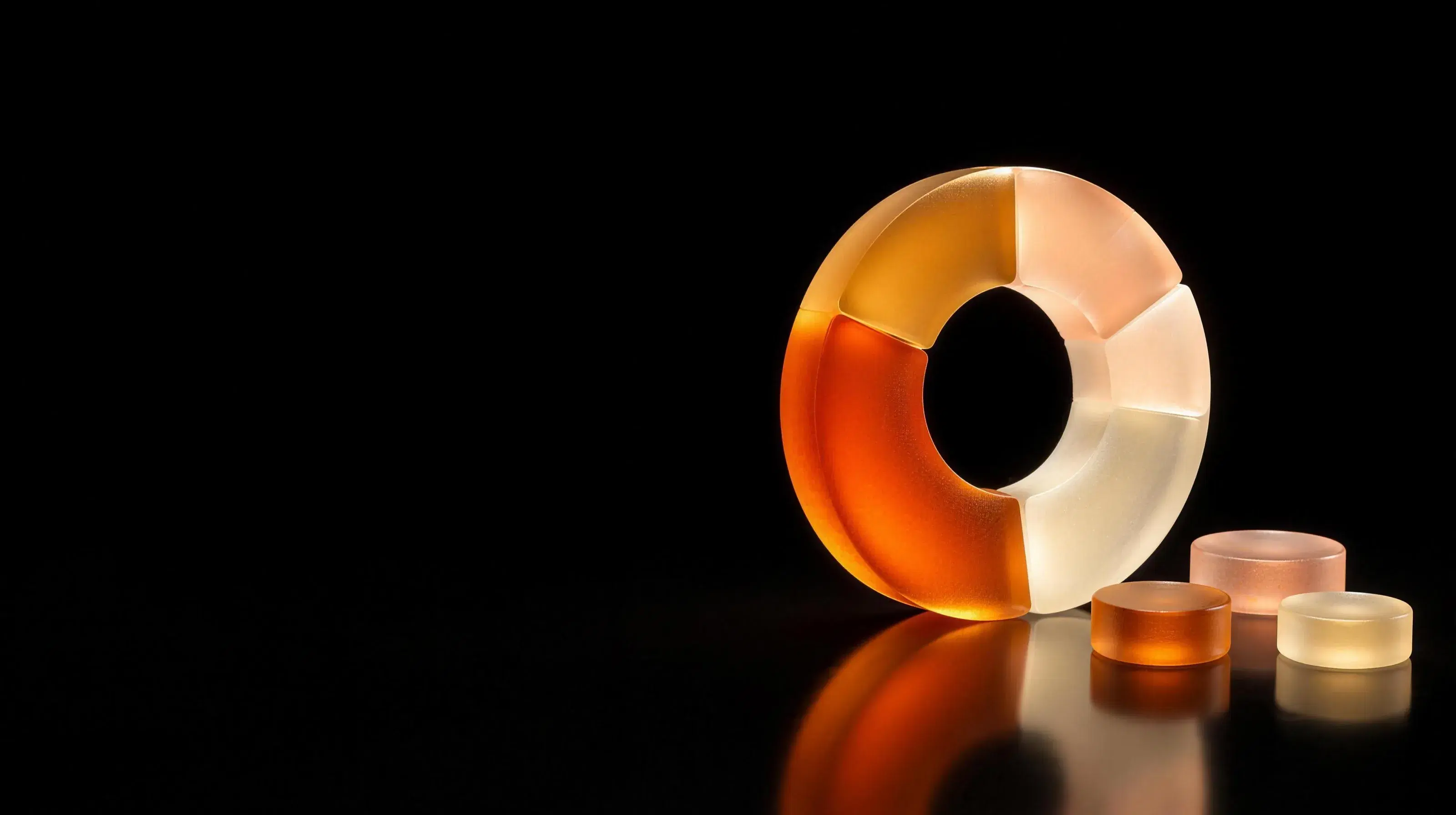 A translucent glass ring split into five segments of different sizes, beside three glass discs